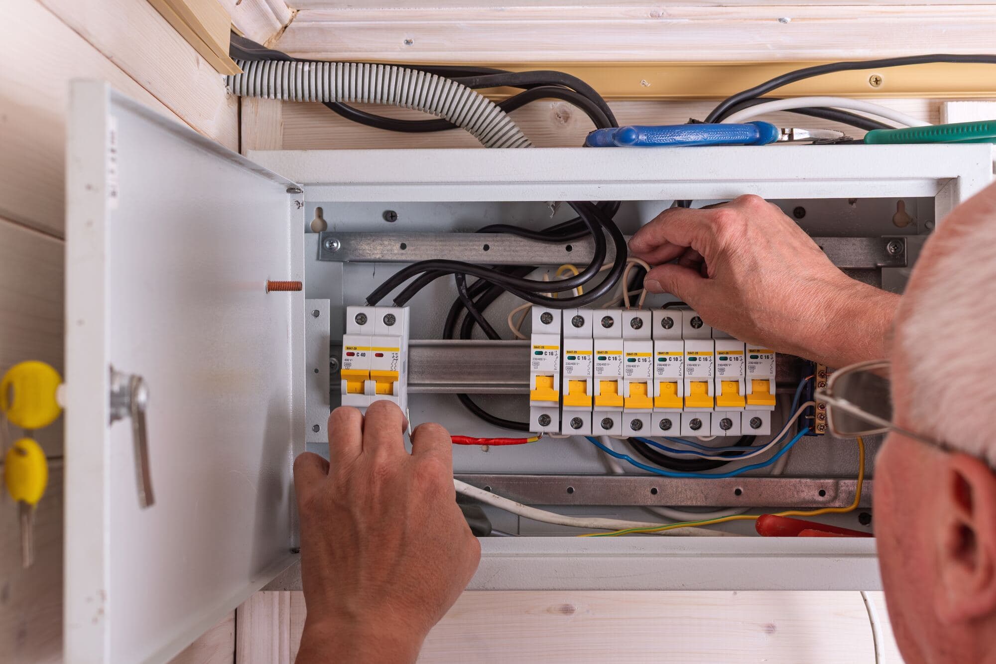 Elektriker justerar automatsäkringar i en öppen elcentral