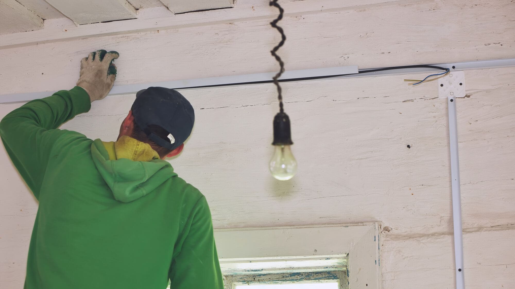 Elektriker drar kabel längs taket i ett trähus