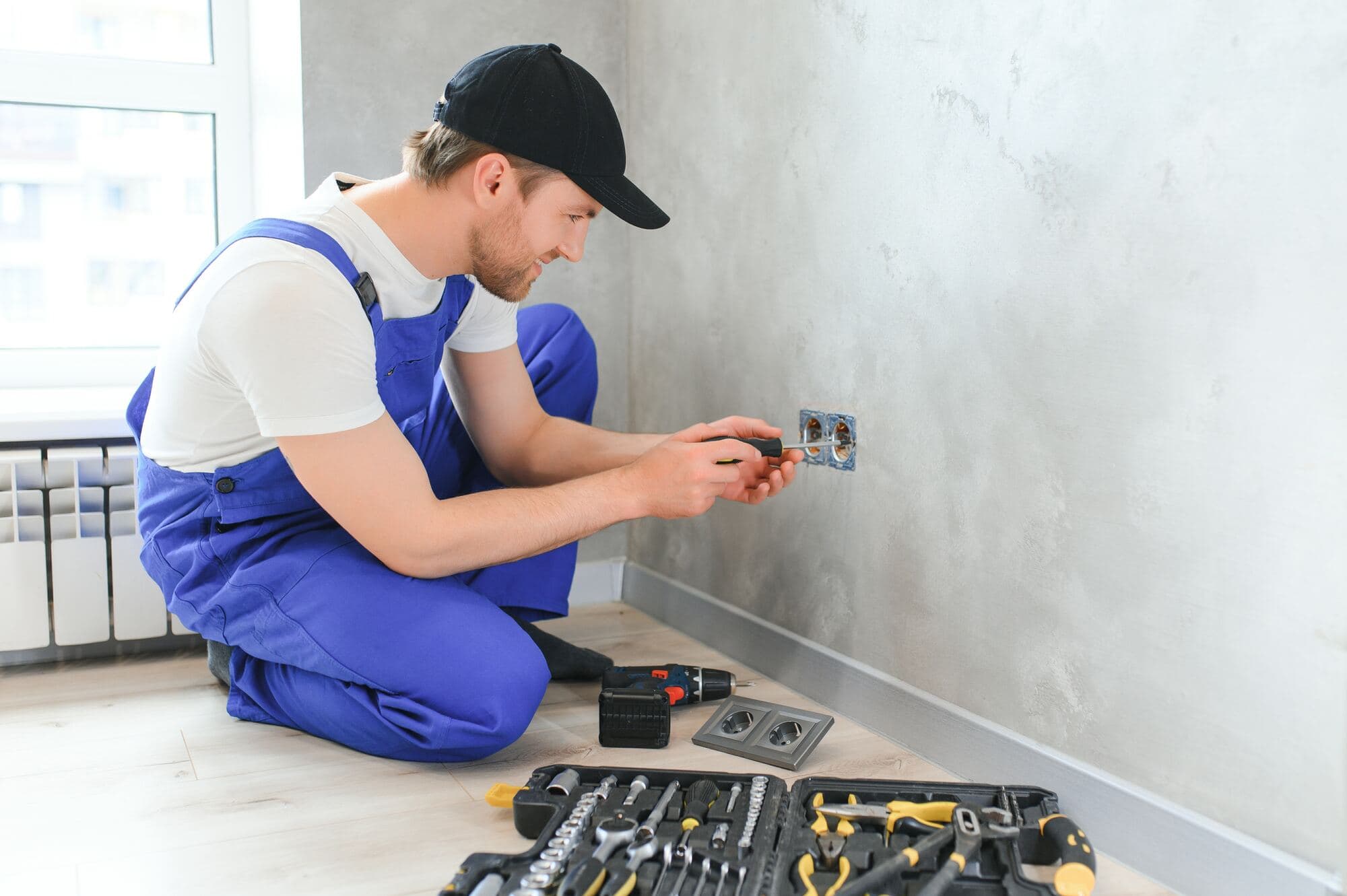 Elektriker monterar uttag vid golvet i en lägenhet under renovering